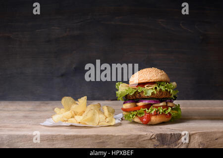 Leckere Burger mit Rindfleisch, Tomaten, Käse, Salat und Pommes Frites auf hölzernen Theke. Kopieren Sie Raum. Stockfoto