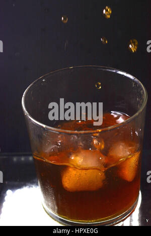 Glas Whiskey mit fallenden Eiswürfel Stockfoto