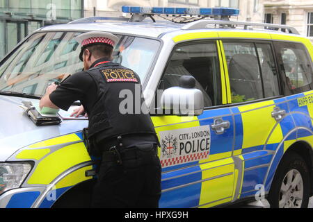 EINE STADT LONDON POLIZIST SCHIEFEN AUF DER MOTORHAUBE EINES POLIZEIAUTOS, EIN TICKET FÜR EINE PROBLEMATISCHE AUTOFAHRER, DIE ER HATTE AUFGEHÖRT ZU SCHREIBEN Stockfoto