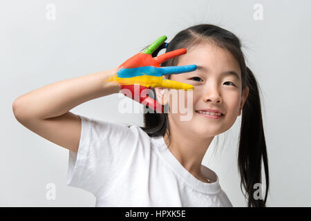 Kleine Asiatin mit Händen in bunten Farben lackiert Stockfoto