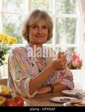 Frau mittleren Alters, trinken Tee mit Keksen, Berkshire, England, Vereinigtes Königreich Stockfoto