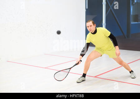 junge kaukasischen Squashspieler Kollision mit einem Ball in einen Squash-Court. Squashspieler in Aktion. Mann Spiel Match Squash Stockfoto