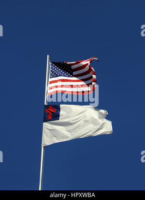 Amerikanische Flagge und christliche Flagge fliegen nebeneinander auf einem Mast in Arkansas.  Sie sind eingerahmt von lebendigen, blauen Himmel und leichter Wind bläst ihnen offen. Stockfoto