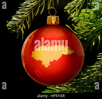 Eine Rote Christbaumkugel mit der goldenen Form von Honduras hängen an einem Weihnachtsbaum isoliert auf schwarz. (Serie) Stockfoto