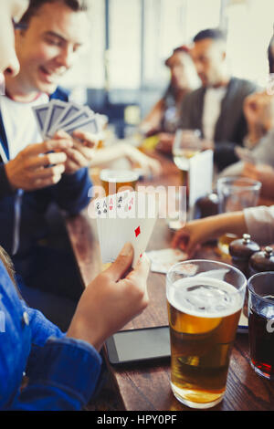 Frau hält Asse Vierling Poker zu spielen und trinken Bier mit Freunden in Bar Stockfoto