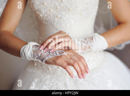 Braut im weißen Kleid bringt Handschuhe auf Händen. Stockfoto