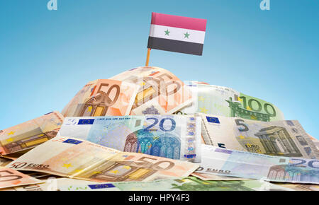 Die Nationalflagge von Syrien in einem Haufen von gemischten europäischen Banknoten kleben. (Serie) Stockfoto