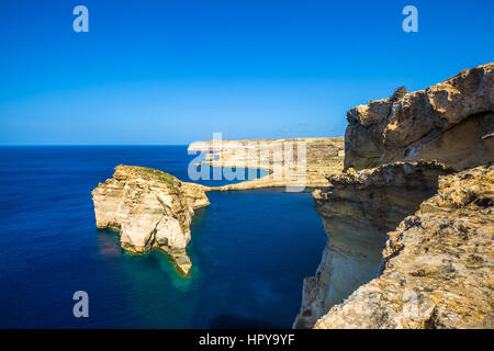 Gozo, Malta - Tha schöne Fungus Rock auf der Insel Gozo mit dem Azure-Fenster im Hintergrund und blauem Himmel Stockfoto