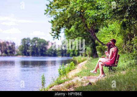 Paar, sitzen auf einer Bank am See an einem sonnigen Sommertag Stockfoto