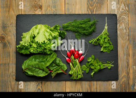 Frischer grüner Salatzutaten, Rucola, Radieschen, Salat, Fenchel und Koriander auf einem Tisch. Ansicht von oben. Stockfoto