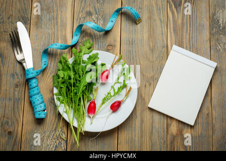 Frische gesunde Salate und Maßband auf rustikalen Tisch. Gesunde Ernährung Draufsicht. Stockfoto