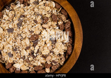 Gesunden Haferflocken Müsli Müsli Müsli mit Schokolade in einer Schüssel auf schwarzem Stein Stockfoto