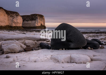 Selwicks Bay in der Morgendämmerung mit schwarzen Steinen auf weiße Kreide, Flamborough, Yorkshire, Großbritannien Stockfoto