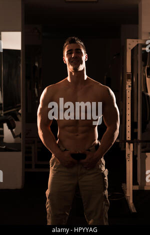 Junger Mann standhaft In der Turnhalle und biegen Muskeln - muskulöse athletische Bodybuilder Fitness Model posiert nach Übungen Stockfoto