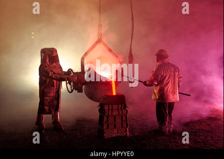 Gießt geschmolzenes Eisen in einem Stahlwerk Reenactment, metallurgische Arbeitnehmer mit Schöpflöffel Löffel, heiß, rauchig, und gefährlich, Bethlehem, Pennsylvania, USA. Stockfoto