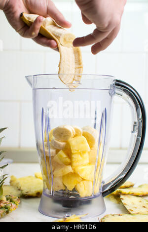 Hand, die Bananenscheiben in einen Mixer hinzufügen Stockfoto