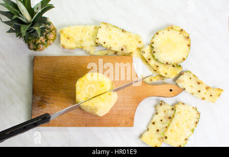 Messer schneiden Ananas auf einem Holzbrett Stockfoto