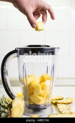 Hand, die Ananasscheiben in einen Mixer hinzufügen Stockfoto