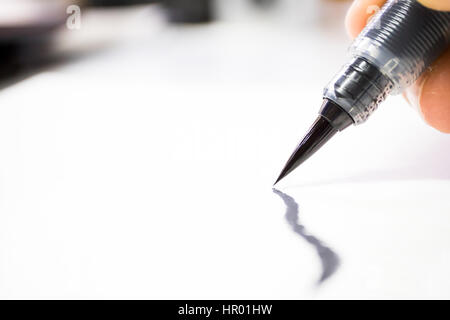 Schwarze Tinte Art Pinsel zeichnen auf weiße Leinwand Papierhintergrund und Textur. Schließen Sie oben und Makro. Stockfoto
