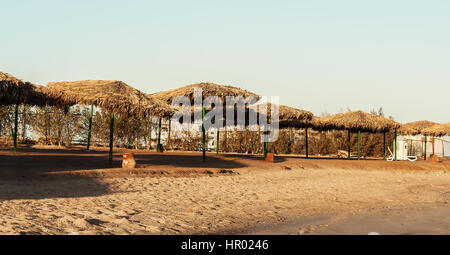 Tag am Strand Stroh Sonnenschirme und Sonnenliegen. Stockfoto