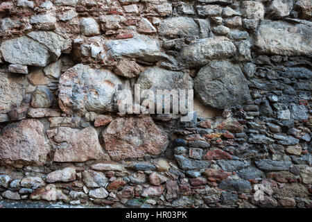 Mittelalterliche Steinmauer Hintergrund oder Textur, die mit großen, mittleren und kleinen Größen der grob geschnittenen Steinen, alten Stadt Girona in Spanien Stockfoto