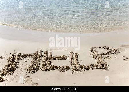 Text Hilfe geätzt in den Sand am Meeresstrand. Bitte um Hilfe um zu überleben. Bitte um Unterstützung an der tropischen Küste. Stockfoto