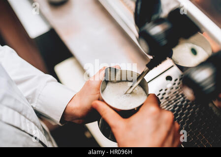 Professionelle Barkeeper Erwärmung von Milch für Cappuccino. Kaffee-Automaten für Latte Art Macchiato Barista. Getönten Bild Stockfoto