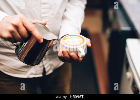 Barista Gießen perfekten Cappuccino in Tasse, wodurch eine köstliche Frühschoppen Stockfoto