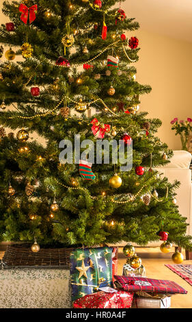 Geschmückte Weihnachtstanne mit Geschenken unter dem Baum in einem Wohnzimmer im Innenbereich des Hauses, Schottland, Großbritannien Stockfoto