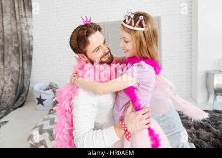 Meine Welt. Junge hübsche Papa tragen rosa Schal und Krone Blick auf seine Tochter umarmt Ihr Stockfoto