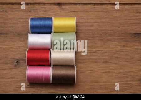 Mehrfarbige Baumwolle Walzen oder Spulen auf einem hölzernen Nähtisch Stockfoto