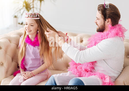 Schönheit-Zeit. Hübscher bärtigen Mann halten rosa Feder um den Hals tragen weiße Brücke halten Haare seiner Tochter in seinen Händen Stockfoto