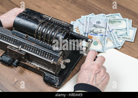 Hände einer alten Frau gezählt auf das Retro-Rechner-Geld, Nahaufnahme Stockfoto