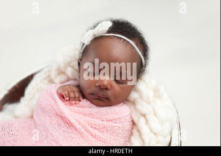 Porträt eines Mädchens einen Monat alt, schlafen, Neugeborenes, Baby. Sie ist in rosa beschützend und schlafen in einem kleinen Eimer. Stockfoto