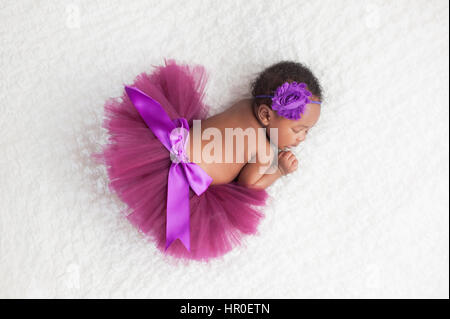 Porträt eines Mädchens einen Monat alt, schlafen, Neugeborenes, Baby. Sie trägt eine lila Tutu und schlafen auf einer weißen Decke. Stockfoto