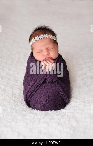 Schlafen, neun Tage alten neugeborenen Mädchen in einem lila Wrap gewickelt. Gedreht im Studio auf einer weißen Decke. Stockfoto