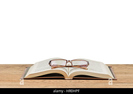 Offenes Buch mit Brille drauf liegen auf dem alten Holztisch auf weißem Hintergrund Stockfoto