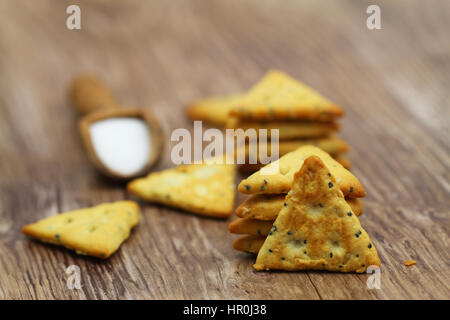 Salzige Snacks Dreiecke mit Mohn und Sesam auf Holzuntergrund Stockfoto
