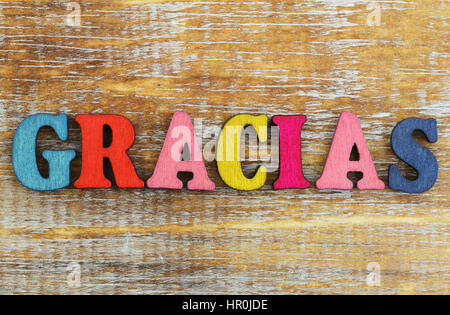 Gracias (Danke auf Spanisch) mit bunten Buchstaben auf rustikalen Holzoberfläche geschrieben Stockfoto