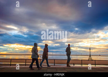 Sonnenuntergang über Crosby, Merseyside. 25. Februar 2017. Menschen Promenade nach einem windig und bitterkalt Tag über den Nordwesten von England, ist ein dramatischer Sonnenuntergang über dem riesigen Windparks installation ruht. Die Burbo Bank Erweiterung Offshore-Windparks Entwicklung besteht aus einer Fläche von 40 km² und einer Kapazität von bis zu 258 MW und erzeugt genug Energie, um die durchschnittlichen Bedarf von bis zu 230.000 Wohnungen zu treffen. Credit: cernan Elias/Alamy leben Nachrichten Stockfoto