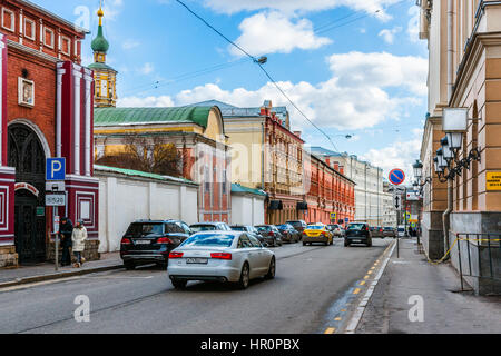 Moskau, Russland. Samstag, 25. Februar 2017. Alten Petrovka-Straße in Richtung des Kreml. Bell Tower des Vysokopetrovsky-Klosters (hohe Stift St. Peter) im Hintergrund. Sonnenlicht überflutet renoviert und restauriert, Straßen und Plätze der Großstadt. Mischung aus alten und neuen Stilen der Architektur und Stil des Lebens. Stockfoto