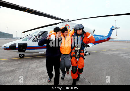 Zhoushan, China Zhejiang Provinz. 25. Februar 2017. Ein Überlebender eines versunkenen Fischerbootes bekommt einen Hubschrauber mit Hilfe auf Putuoshan Flughafen in Zhoushan Stadt, Ost-China Zhejiang Provinz, 25. Februar 2017. Ein Boot sank 130 Seemeilen östlich von Zhoushan Stadt, Provinz Zhejiang, am Freitag. Eine kombinierte Rettung von militärischen und zivilen Anstrengungen geborgen sieben Personen, während der Rest der 13 Besatzungsmitglieder bleiben vermisst. Bildnachweis: Hua Zhibo/Xinhua/Alamy Live-Nachrichten Stockfoto