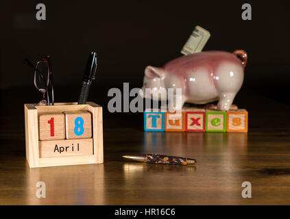 Holzbuchstaben in Kalender zeigt Steuer-Tag für die Einreichung ist 18. April 2017 mit Piggy Sparkasse im Hintergrund Stockfoto