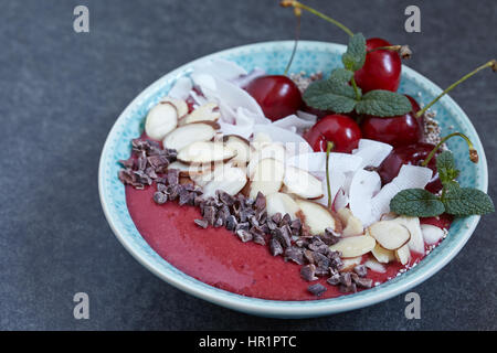 Smoothie-Schüssel garniert mit Kirsche, Kokos und Mandel Stockfoto