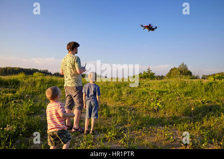 Vater und Sohn Steuerelemente RC Drone Quadrocopter in den Himmel Stockfoto