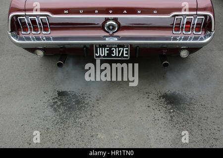 1967 klassische Burgunder Ford Mustang Coupe mit Wasser im Abgas Rauch als der V8 Motor sich erwärmt Stockfoto