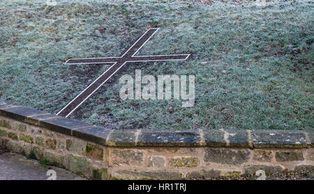 Frost an einem ruhigen Winter Morgen auf einen schönen Stein Überblick über ein Kreuz gesetzt im Gras am St.-Lorenz-Kirche, Mickleton, Gloucestershire Stockfoto