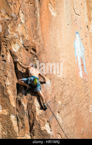 Junger Mann Klettern von der Jungfrau von Guadalupe Malerei; Penitente Canyon; Colorado; USA Stockfoto