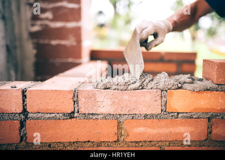 industrielle Bauarbeiter Maurer Mauern bauen mit Ziegel, Mörtel und Kitt Messer Stockfoto