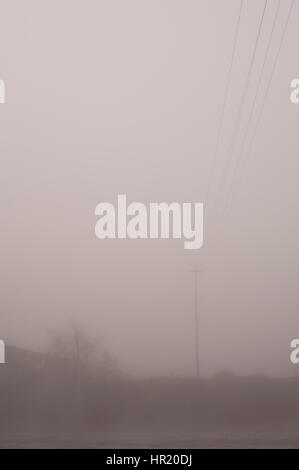 Sonnenaufgang im Nebel mit Stromleitungen Rückzug aus in dunstigen Licht Stockfoto